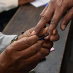 A polling official applies indelible phosphorus ink on the fore finger of a voter - Bengaluru News in Hindi