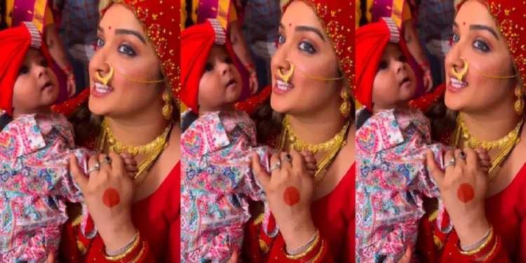 Amrapali Dubey, laden with gold jewelery in the bride's couple, is seen feeding the child in the lap